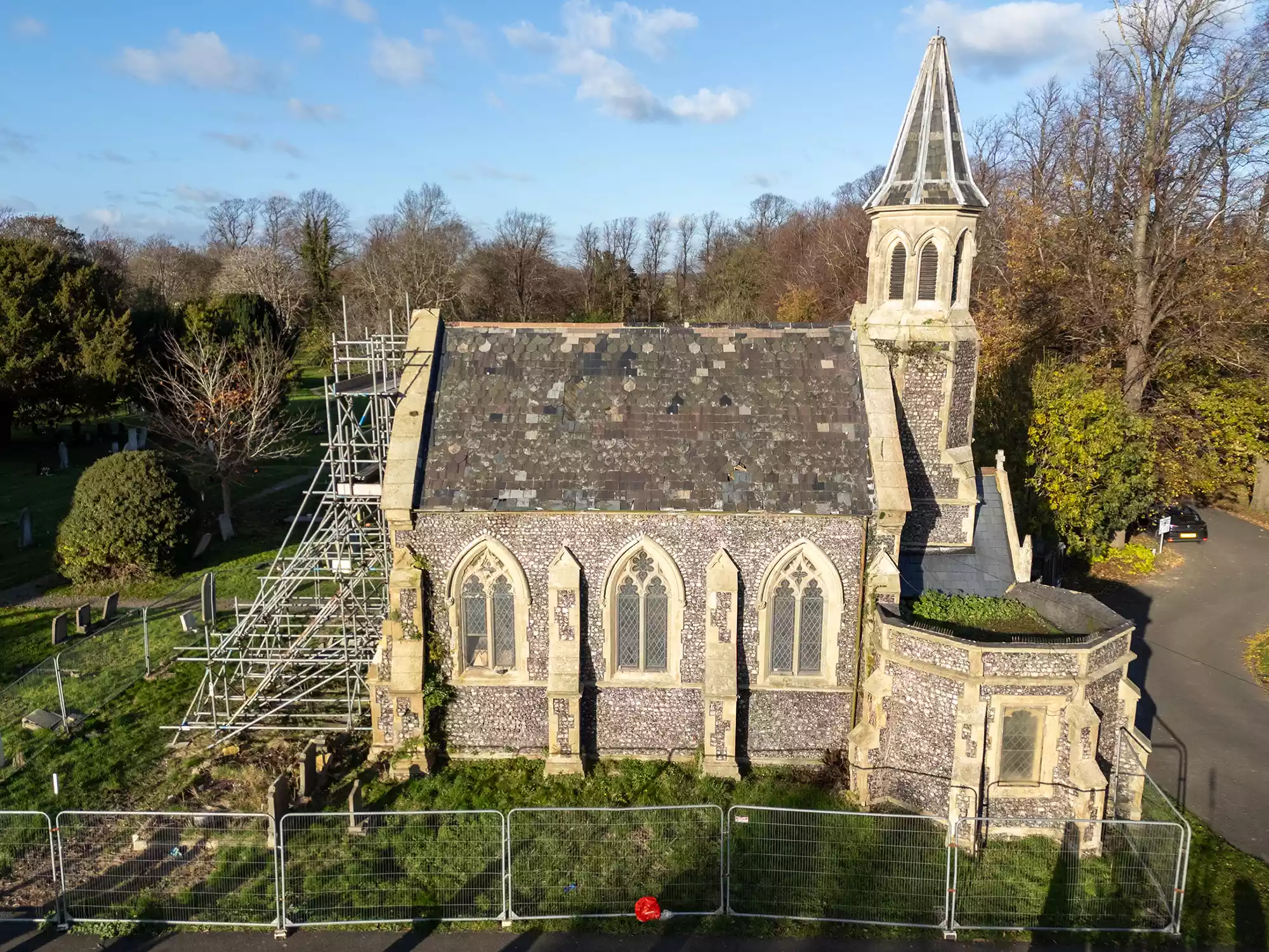 Aerial view of a chapel roof and stone tower with scaffolding alongside