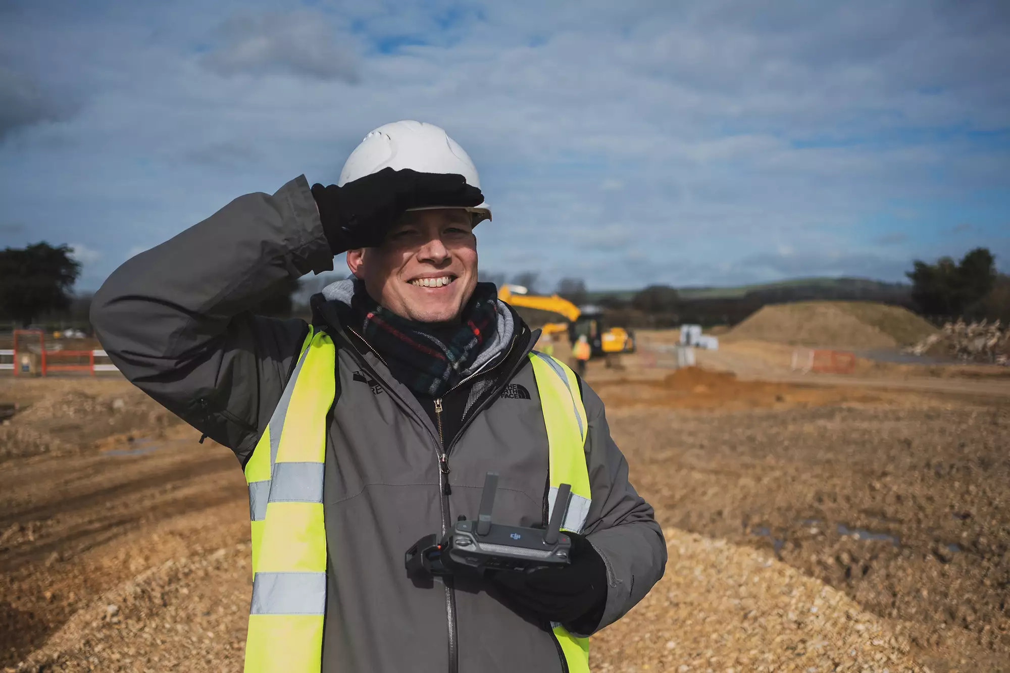 Surveyor wearing a hard hat and high-visibility vest on a construction site