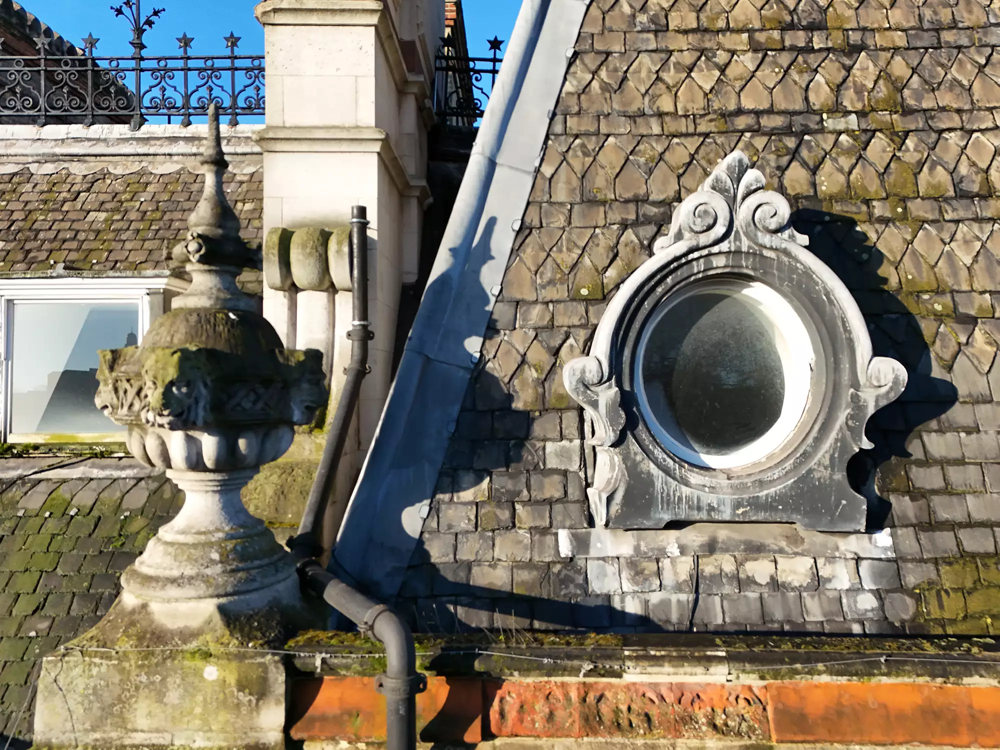 Close-up aerial view of roof tiles, stonework and a circular window